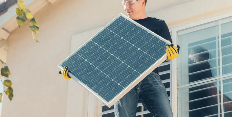 A solar specialist carrying a panel.